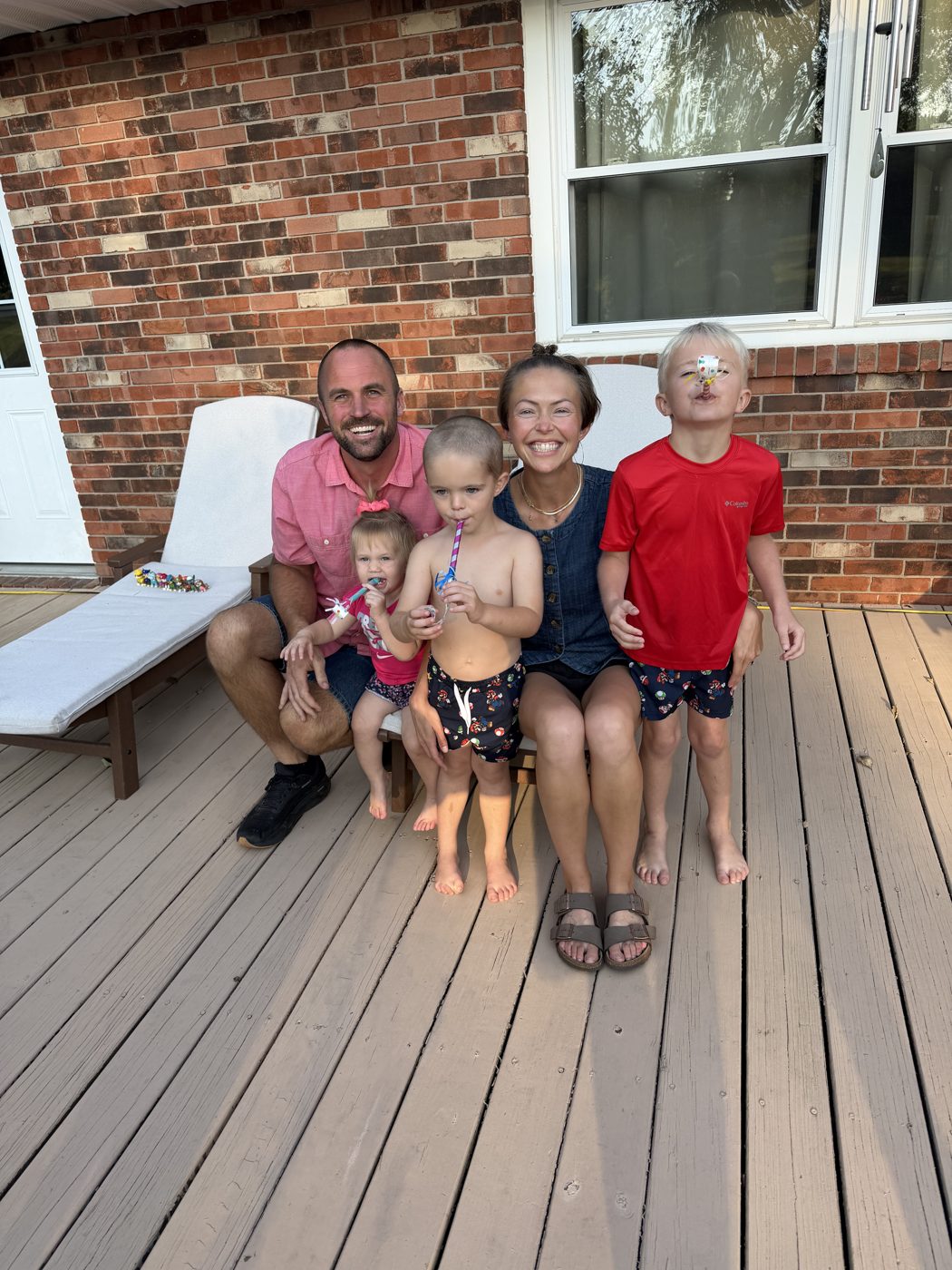 Aaron with his family, smiling together on the back deck